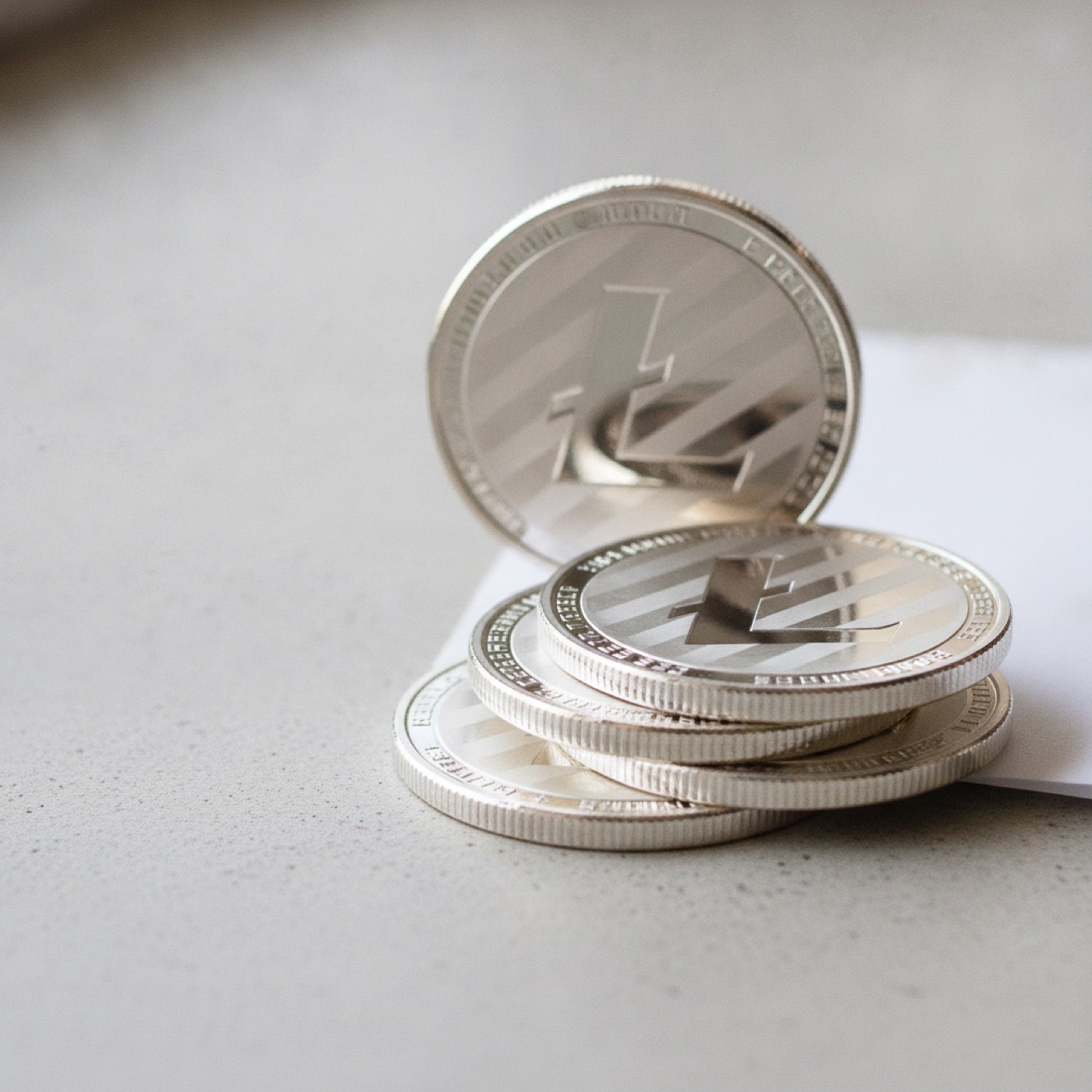 A stack of silver Litecoin coins with one standing on edge behind them